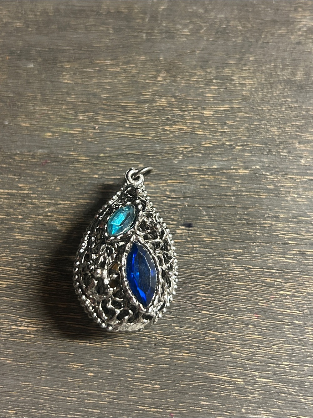 Victorian-style pendant features a teardrop-shaped blue crystal silver filigree